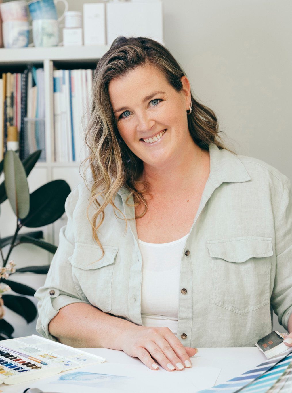 Bec smiling at her studio desk with paint swatches