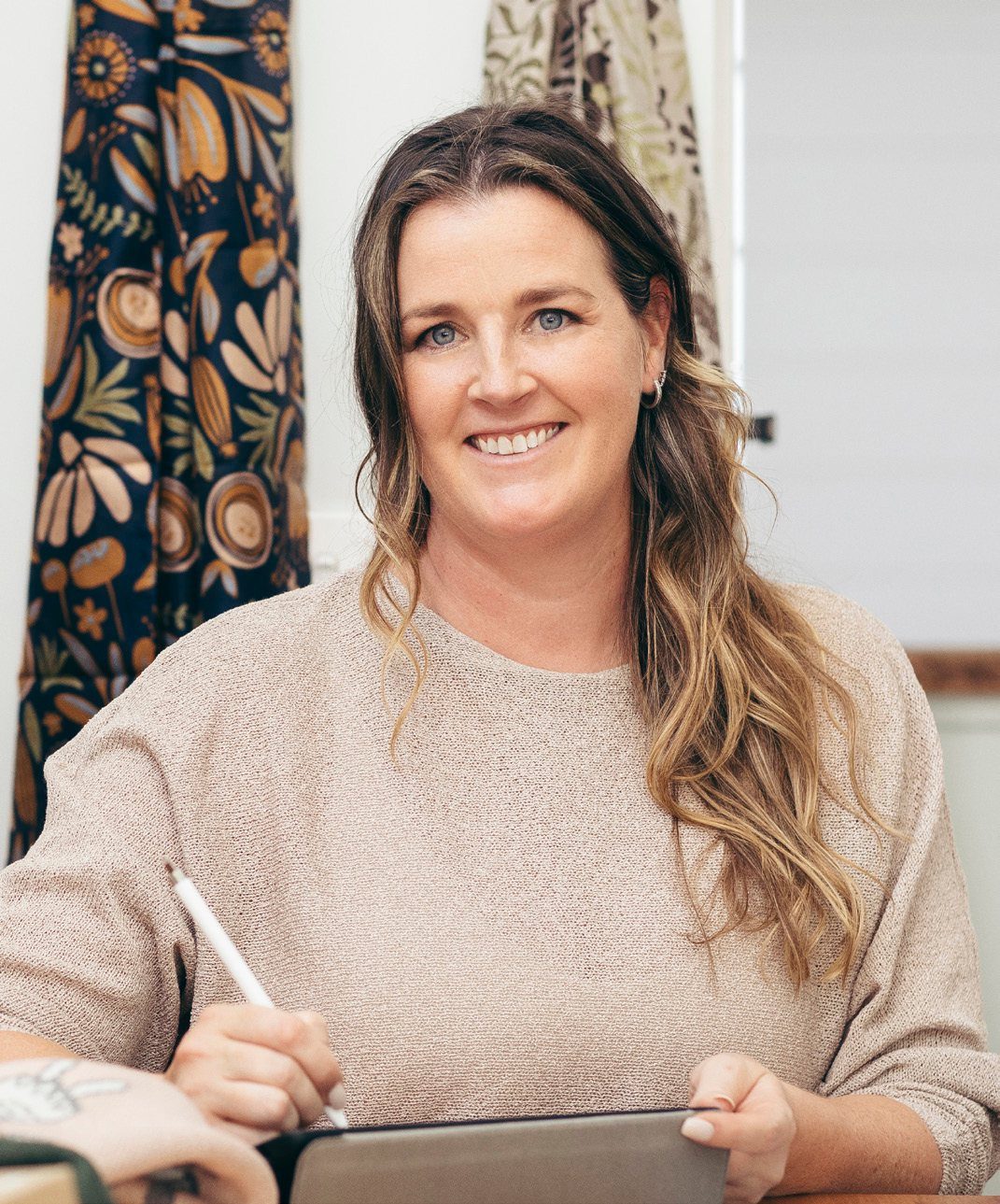Bec smiling at her desk with a stylus and tablet