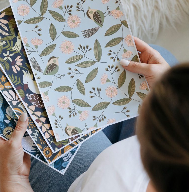 Hands flipping through printed botanical pattern swatches
