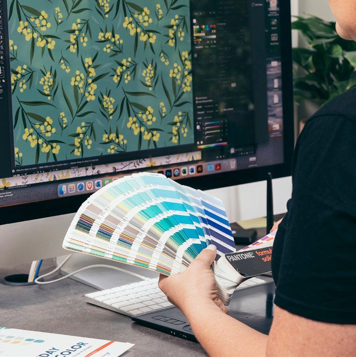 Designer comparing colour swatches against a pattern on screen