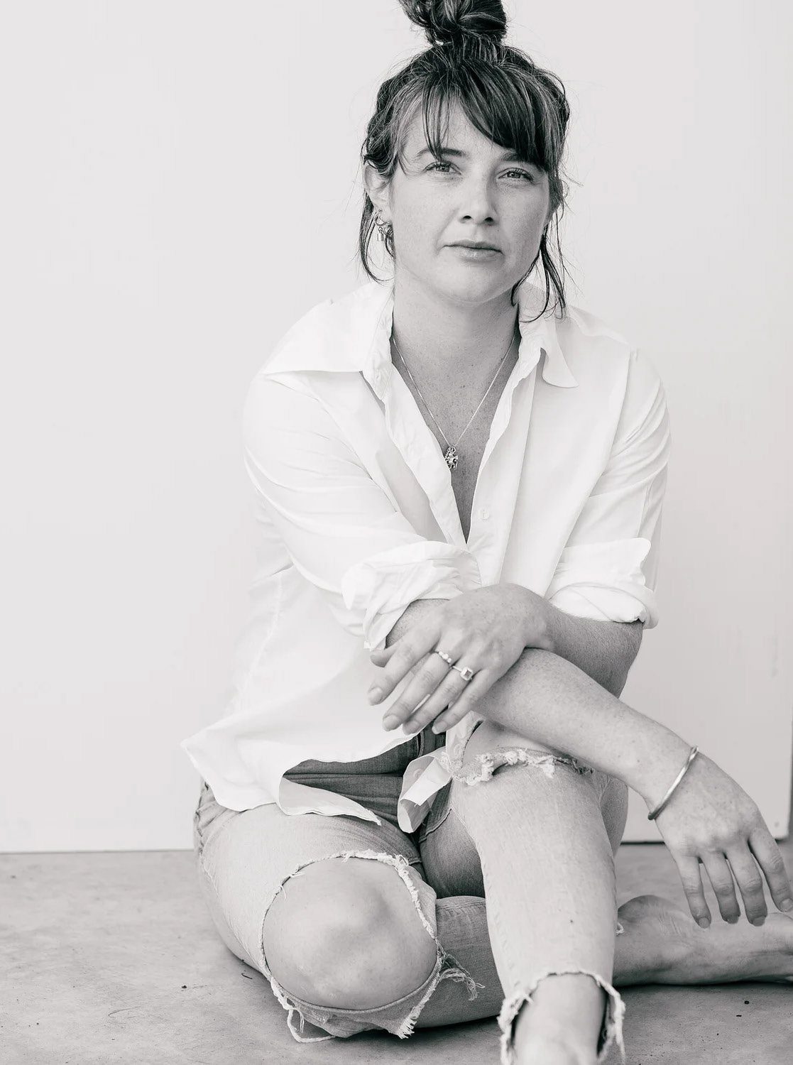 Black and white portrait of Tara seated on a studio floor